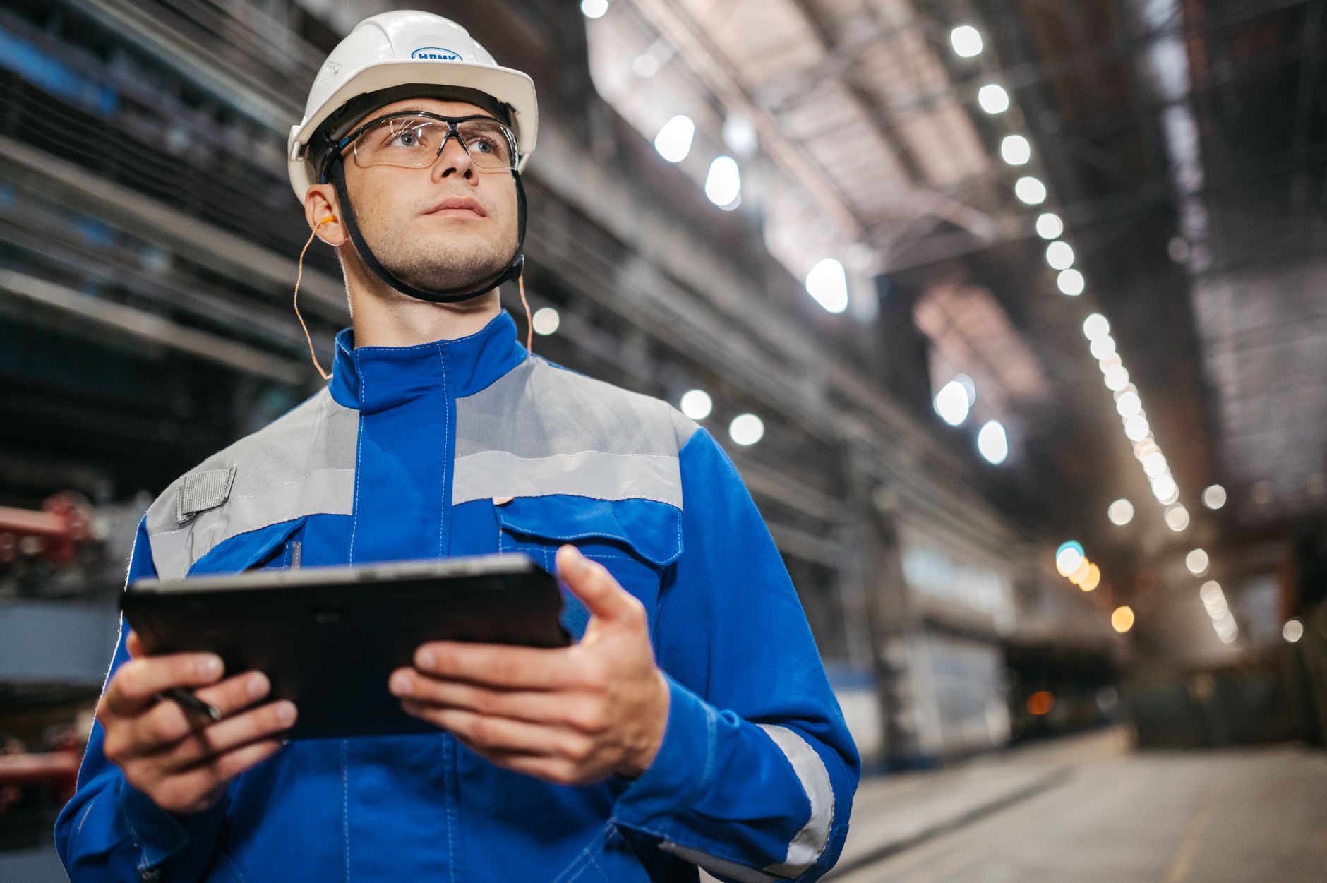 Operador de galpão industrial com equipamento de proteção usando um tablet durante o trabalho