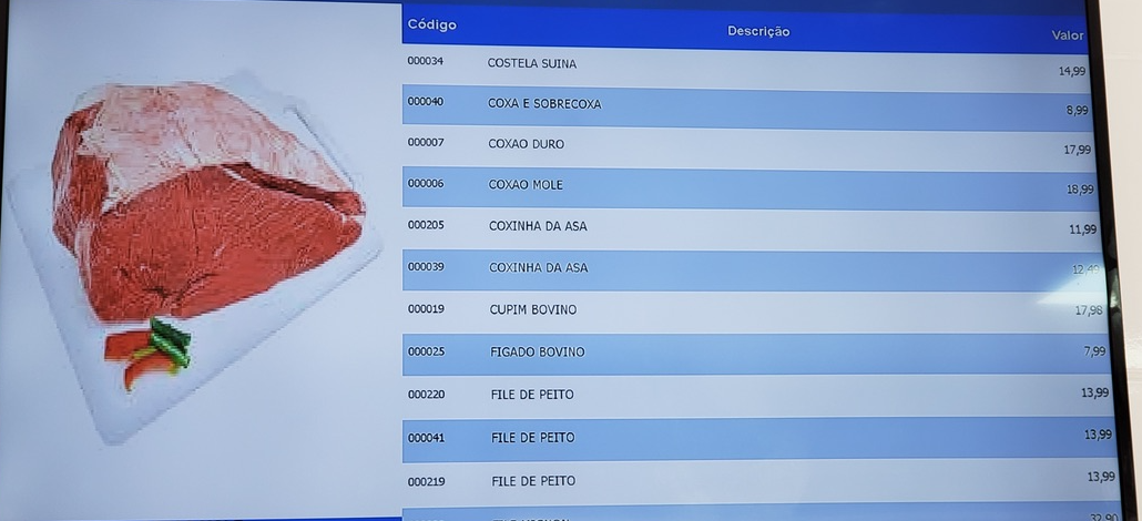 Televisão exibindo a tabela de preços do MIDMAX, com código, descrição e valor de cada produto